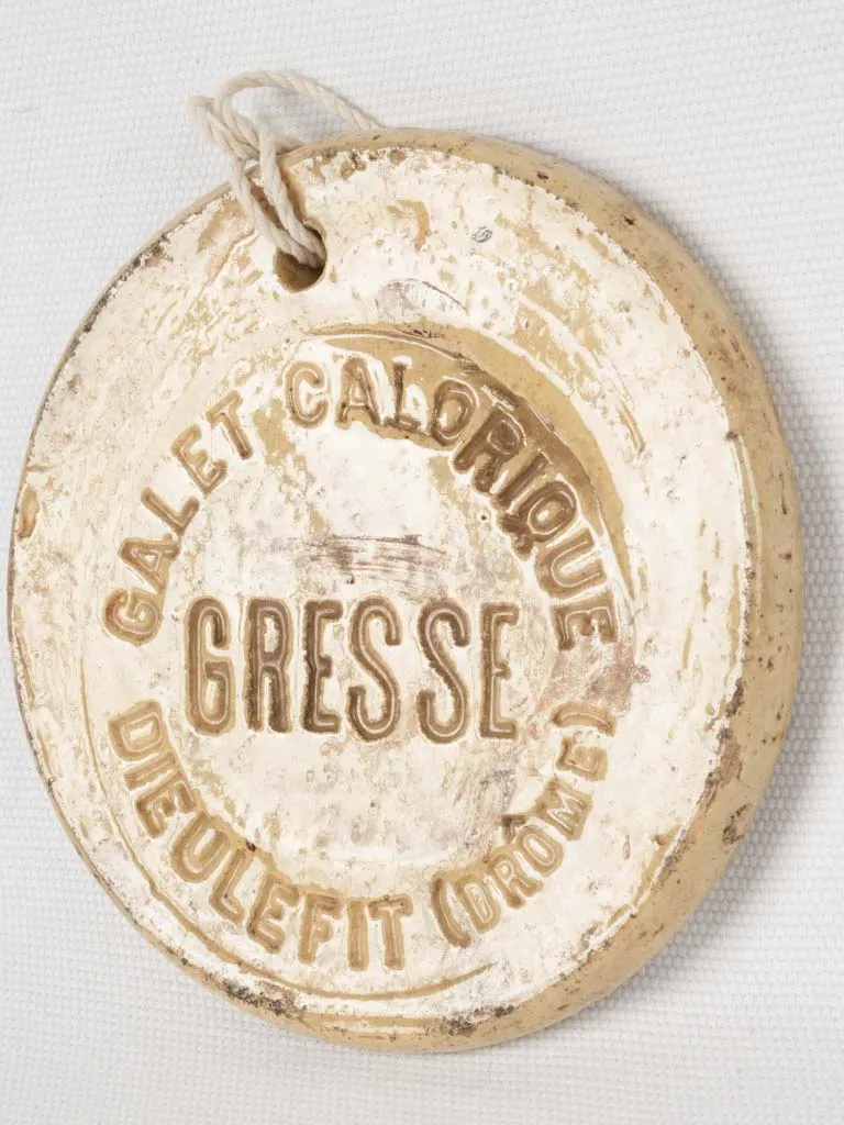 Antique French yellow “Galet calorifique” stamped medallion w/ string